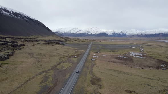 Following a highway across brown autumn ground towards glorious snow capped mountains