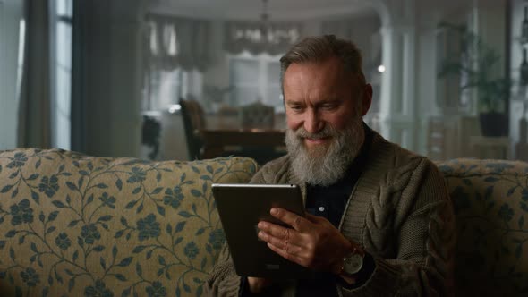 Smiling Old Man Reading News Online Tablet Computer