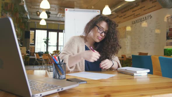 Young Happy Woman Working in the Office Writing Something and Using Computer