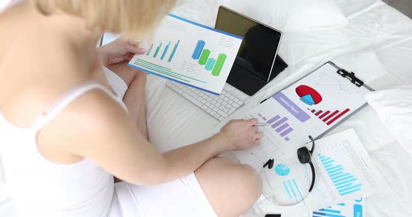 Woman Sitting on Bed with Lot of Documents with Graphs and Diagrams  Movie