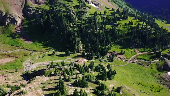 Aerial View of Drone Flying Above Mountain Valley filled with trees and dirt roads 