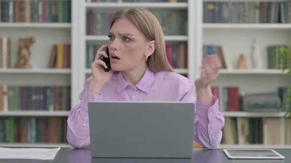 Angry Woman Talking on Phone at Work