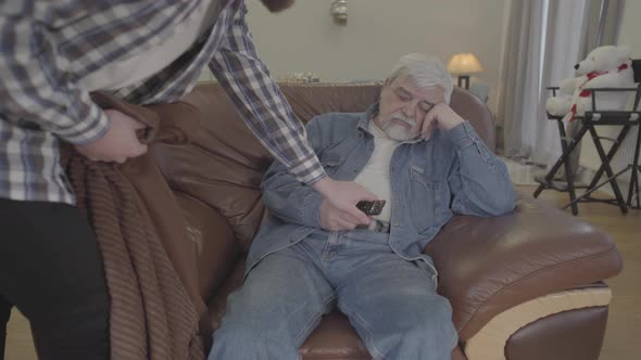 Portrait of Mature Grey-haired Caucasian Man Sleeping on Armchair with Remote Control As Adult