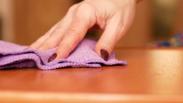 Close-up of a woman's hand cleaning and wiping the furniture with a microfiber cloth.