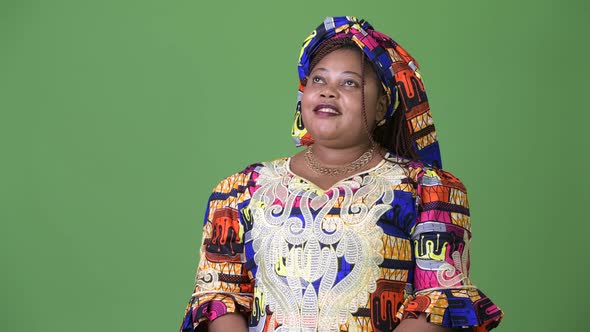 Overweight Beautiful African Woman Wearing Traditional Clothing Against Green Background