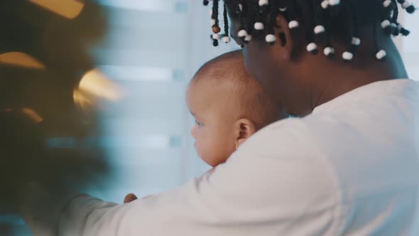 Caring African American Father Cuddling His Newborn Baby Near Christmas Tree