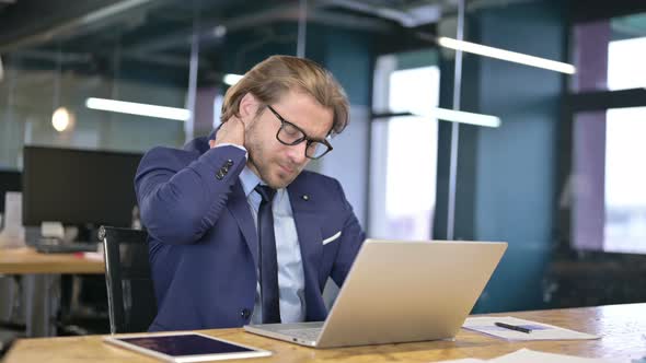 Tired Businessman Having Neck Pain in Office