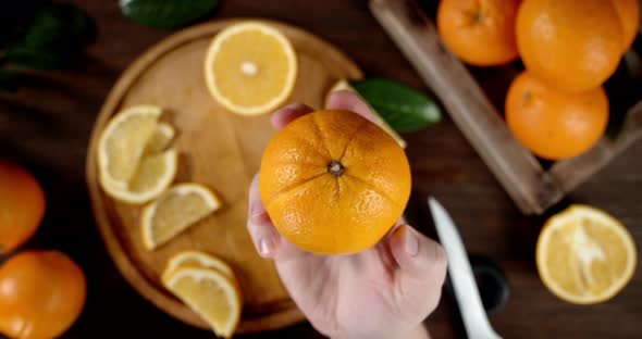 Male Hand Puts a Juicy Orange on a Cutting Board. 