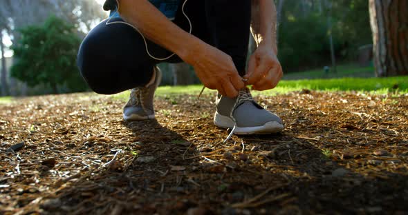 Senior woman tying shoe laces in the park 4k