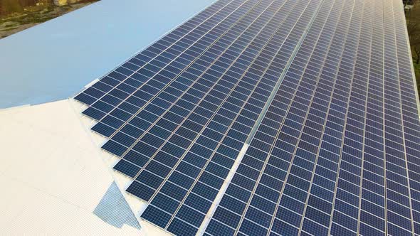 Aerial view of surface of blue photovoltaic solar panels mounted on building roof for producing