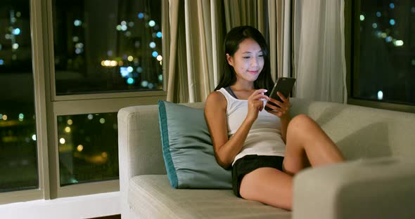 Woman using mobile phone and sitting on sofa 