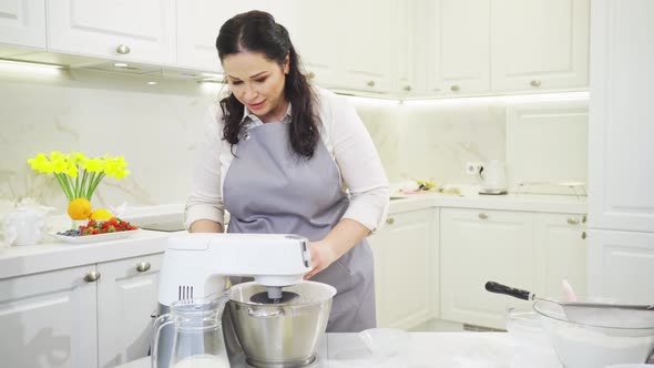 A Woman Cook Adds a Vanilla Sugar to Prepare Dough in a Mixer Bowl