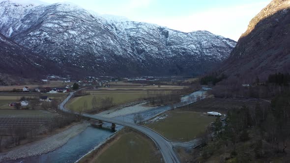 Road E16 passing on bridge over Laerdal river - Ascending aerial after sunset in valley looking towa