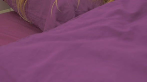 Blonde girl dreaming in the bed with purple covers  slow panning 4K 2160p UHD footage - Woman sleapi