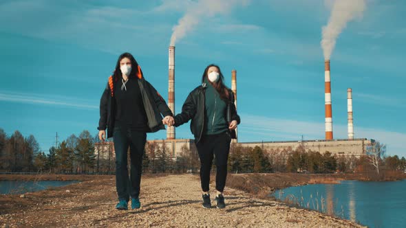 Two Residents of an Industrial City, a Man and a Woman, Run in Respirators Along a Dirt Road Along