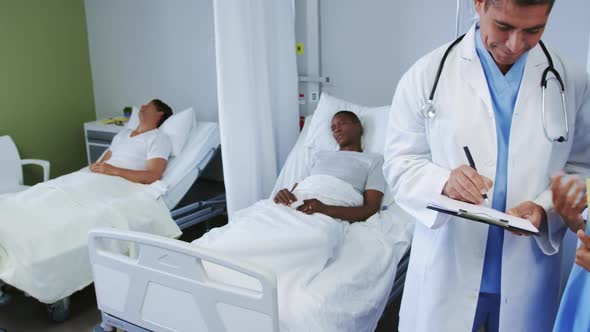 Front view of multi-ethnic doctors discussing over clipboard in ward at hospital