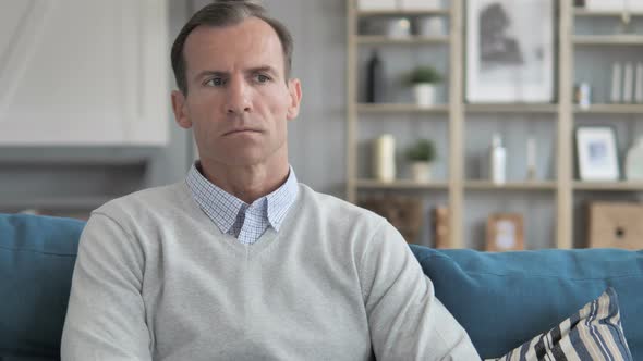 Pensive Middle Aged Man Sitting on Couch in Creative Office