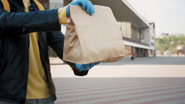 Close Up Shot of Courier Wearing Gloves Gives Delivery Package to Customer Outdoors in the City Slow