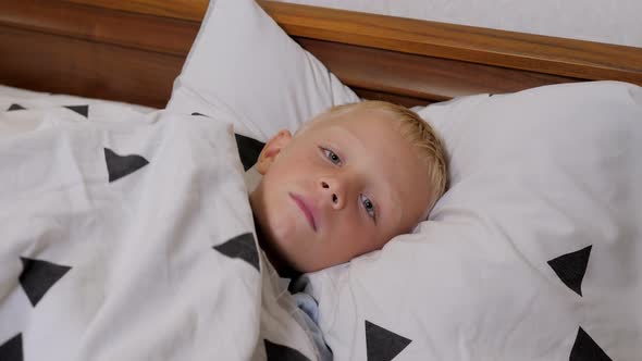 A Little Boy with a Fever is Sleeping in a Bed at Home