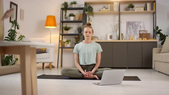 Woman Meditating at Home during Online Yoga Class