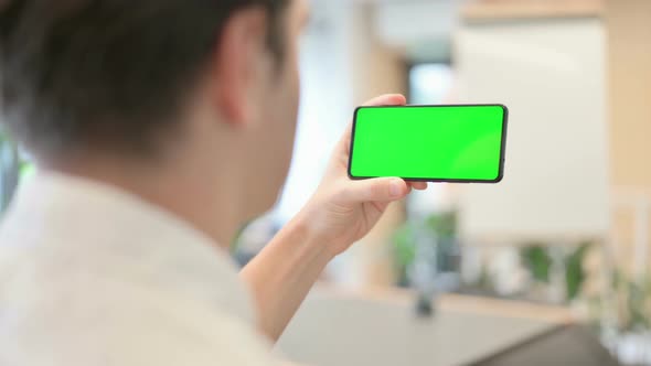 Young Man Looking at Smartphone with Green Chroma Screen
