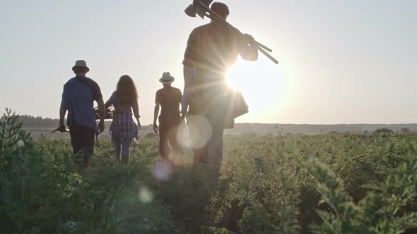 Farmers with Tools Walking through Green Grass