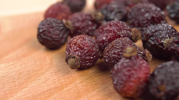 Dried red wrinkled rose hips on a wooden surface