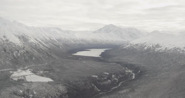 Aerial helicopter flyover of Alaskan river, passing mountains, drone footage