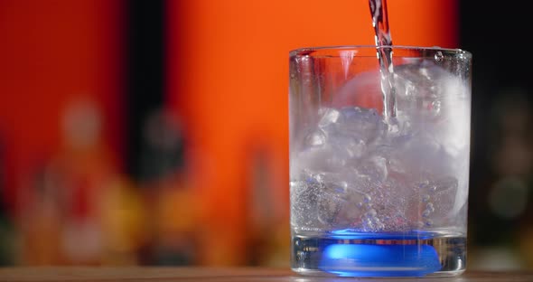 Barman Pours Transparent Liquid to the Cocktail Glass with Ice Cubes in Slow Motion Making the