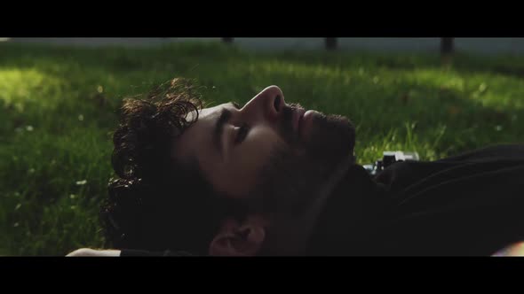 Man resting on his back on grass next to his camera