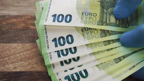 A man holds euro banknotes in the hands of wearing medical protective gloves