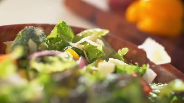 Camera follows parmesan cheese being put on salad. 4K 30fps. Slow Motion.