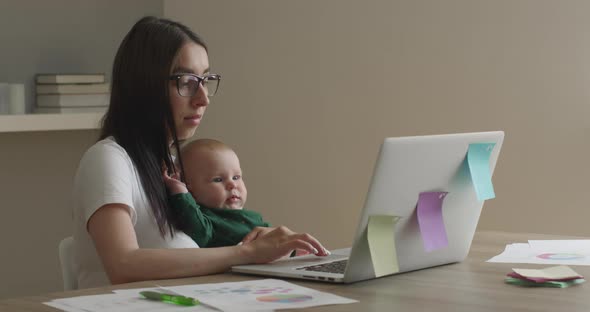 The Mother with Glasses Is Working on a Laptop