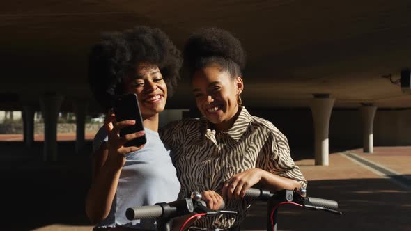 Two mixed race women taking picture under bridge