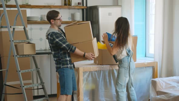 Happy Couple Packing and Carrying Boxes Moving in New House Together