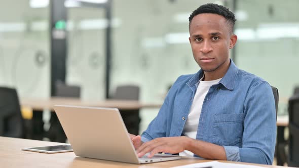 Serious Casual African Man with Laptop Looking at the Camera 