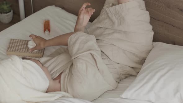 Young Woman after Bath Applying Hand Cream Lying in Bed