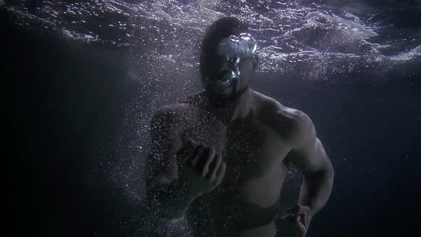 A Muscular African American Under Water with a Naked Torso Screams and Shows Emotions of Pain