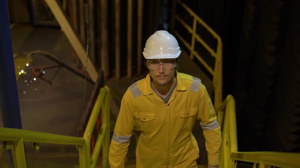 Young Man in a Yellow Work Uniform, Glasses and Helmet in Industrial Environment,oil Platform or