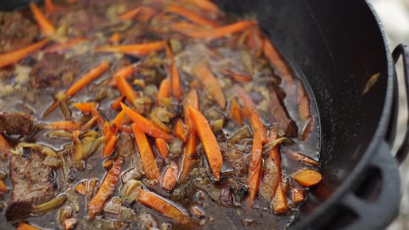 Stewing Carrots with Meat in Fat for Uzbek Pilaf in a Cauldron