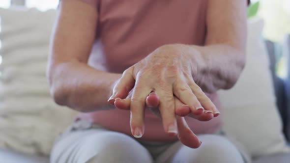 Mid section of senior woman sanitizing her hands at home