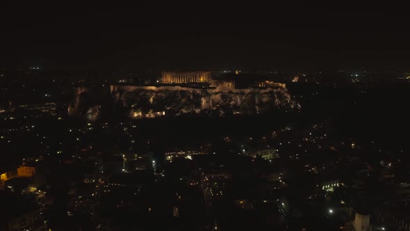 Aerial view of the parthenon temple on acropolis hill at night in Athens.