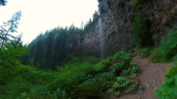 Walking view of Watson Waterfall in Oregon seen from a hiker's back.