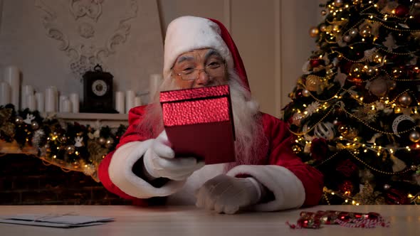 Smiling Santa Claus Gives Gift in Festive Red Box Christmas Winter Holidays