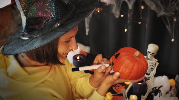 Halloween. Happy cheerful girl preparing for Halloween, painting pumpkin face