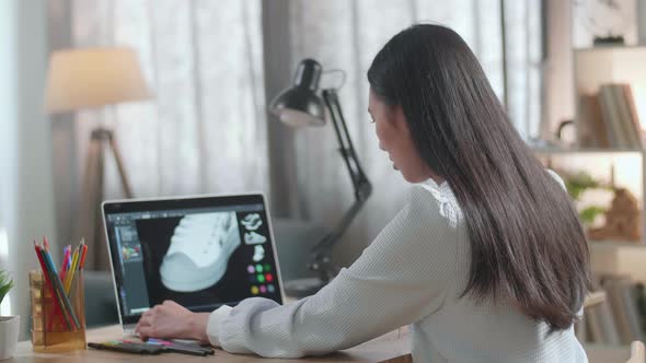 Asian Female Footwear Designer 3D Model Of Shoe While Working On A Laptop