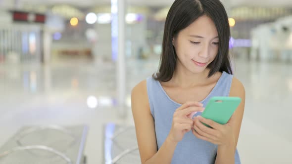 Woman working on cellphone in airport 