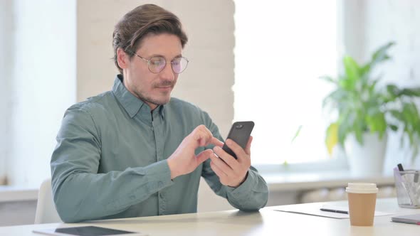 Attractive Middle Aged Man Using Smartphone in Office