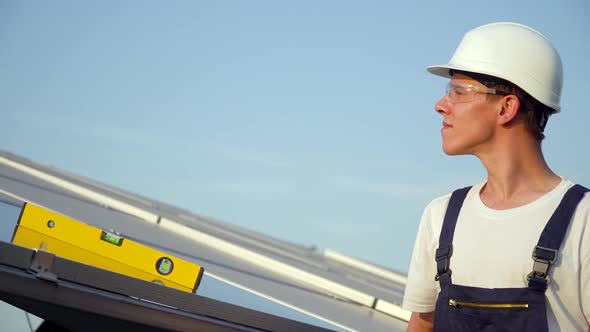 Young Enginneer Installing New Sunny Batteries. Worker in a Uniform and Hardhat Installing