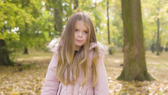 Cute Little Caucasian Girl Acts Shy in a Park